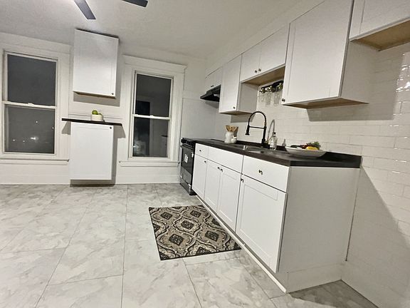 spacious newly remodeled eat in kitchen with modern white subway tile, waterproof vinyl flooring new glass top stove and over the range microwave