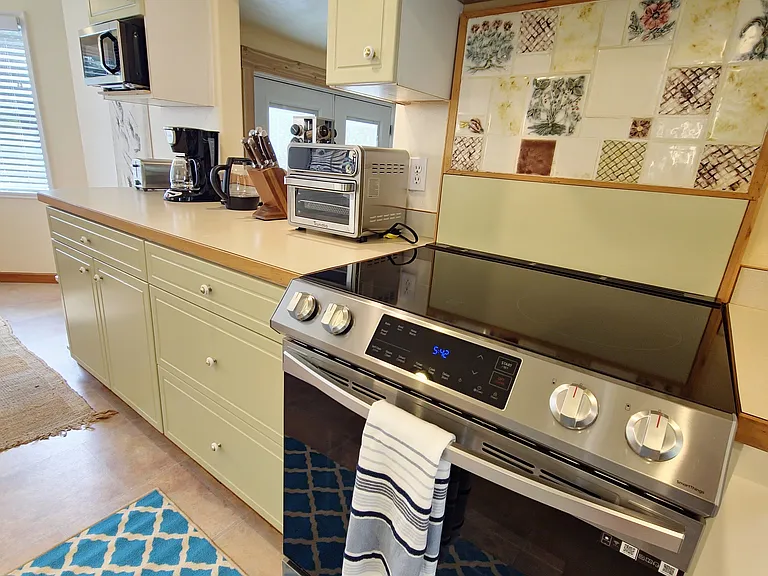 Galley kitchen with new dishwasher, induction range, microwave and numerous accessories.