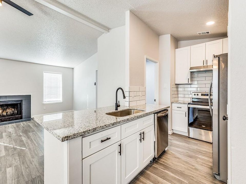 Kitchen with a textured ceiling, white cabinets, open floor plan, light wood-style flooring, and light stone counters