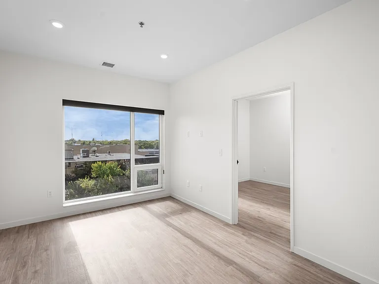 Bright, modern bedroom with large window and hardwood floors, offering a serene view and ample natural light. Bright, modern bedroom with large window and hardwood floors, offering a serene view and ample natural light.