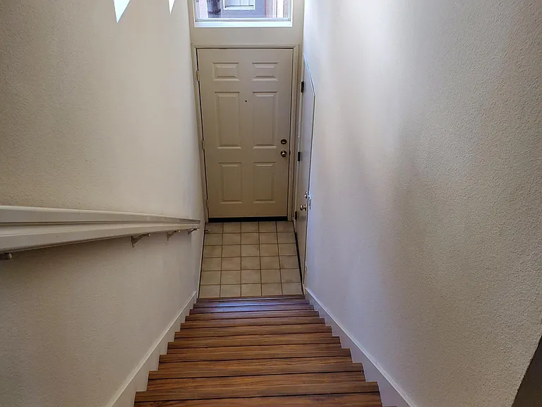 Entrance door to unit and indoor stairs leading up to the unit. Garage is the door to the right at bottom of stairs.