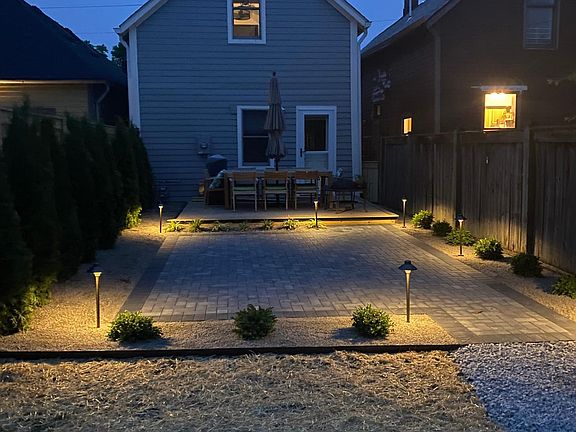 back of house in the evening 
 ground lights stay! boxwood bushes have been pulled and permanent planters installed instead