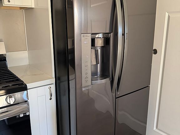 A new and large refrigerator with a water filter and an ice maker.