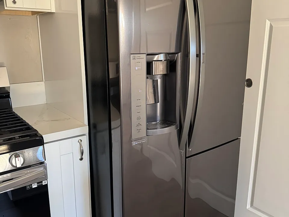 A new and large refrigerator with a water filter and an ice maker.