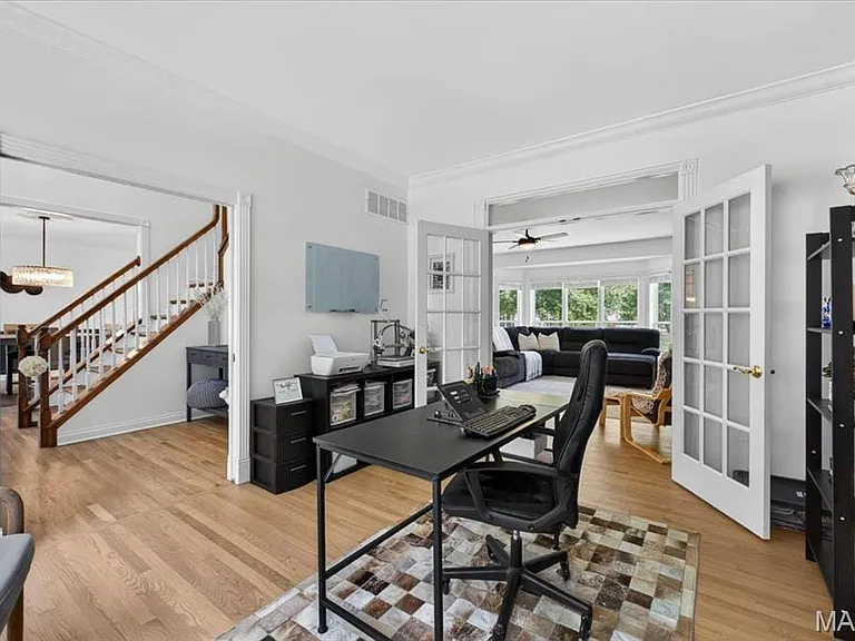 Light wood-finish flooring throughout, featuring a white spindle staircase with wood handrails