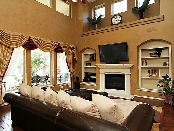 THE SPACIOUS TWO STORY FAMILY ROOM IS BEAUTIFULLY ENHANCED WITH AN ATTRACTIVE STONE FIREPLACE SURROUNDED BY CUSTOM SHELVING...AND ASTOUNDING VIEWS OF THE OUTDOORS.