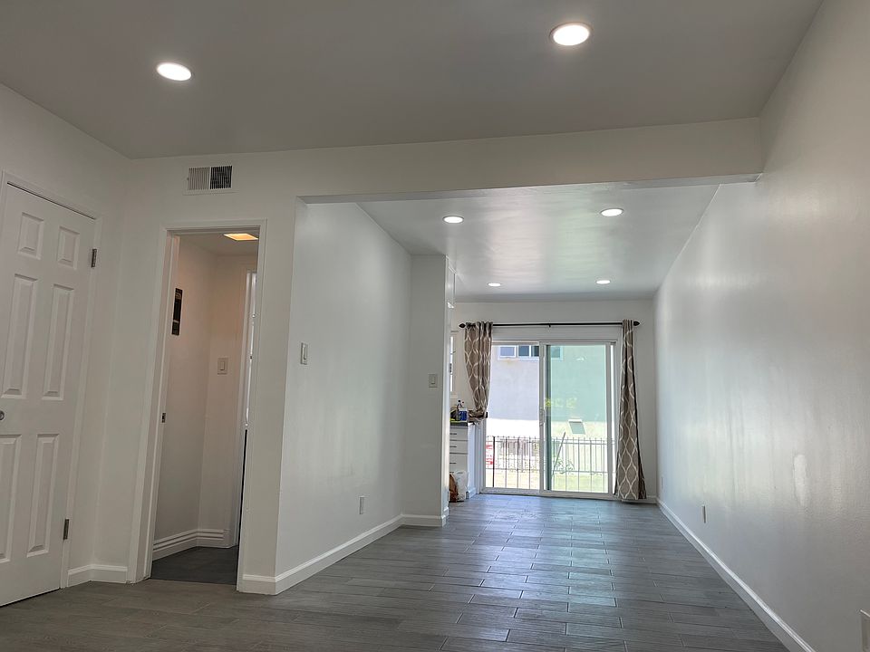 Looking from living room towards kitchen/dining area and sliding glass door entrance. Open door to the left leads to the downstairs bathroom.