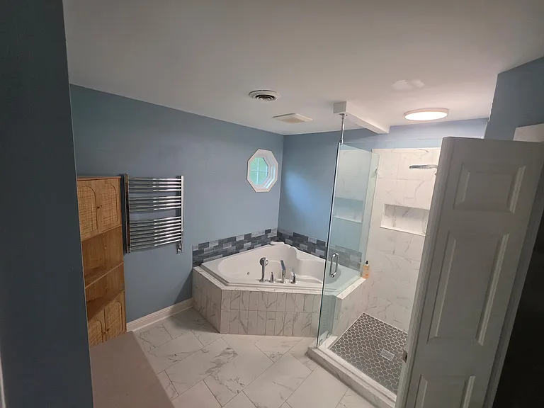 Another angle looking at the Primary Bathroom. Wall-mounted towel heater rack; 2-person jetted air-bubbled corner tub; tiled stand-in shower