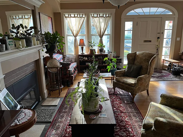 Main Parlor | Huge primary living room with comfy couches, wingback chairs, a gaggle of houseplants, and chill lounge vibes.