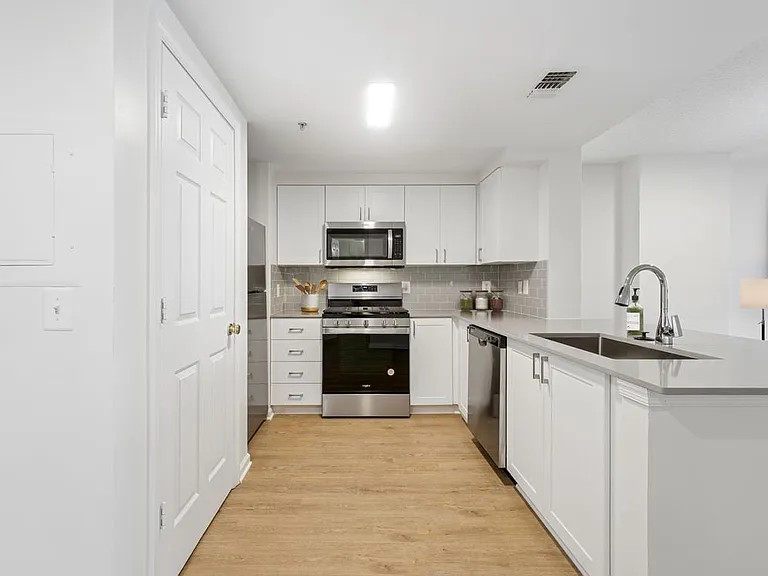 Renovated Package II kitchen with white cabinetry, grey quartz countertops, grey subway tile backsplash, stainless steel appliances, and hard surface flooring