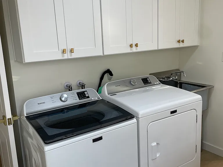 custom cabinetry, quartz countertop, utility sink, and wall-mounted shelves