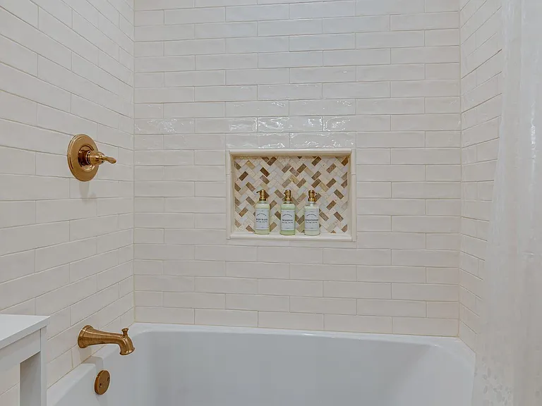 Shower/tub is oversized for wide tub soaks. Goldtone fixtures, elegant tiling and included shampoo, conditioner and soap to get you started