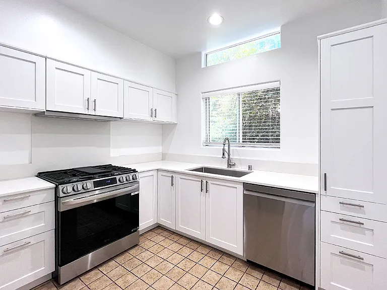 Fully renovated kitchen featuring a premium LG gas stove, a chef-level sink and faucet, and a peaceful window view over brand-new quartz countertops.