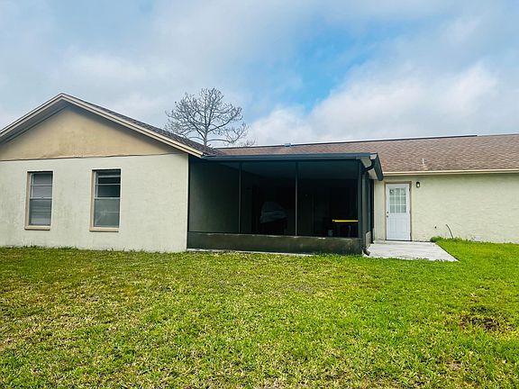 Back of home, screened lanai with a paved entry-way.