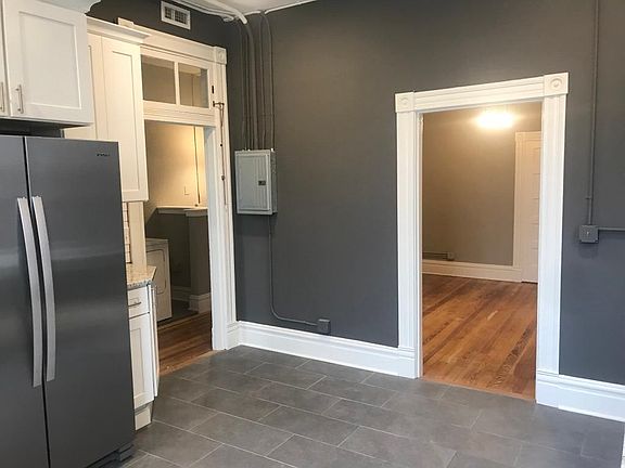 Kitchen looking toward laundry and dining/living room. Restored historic trim, transom, and wood floors.