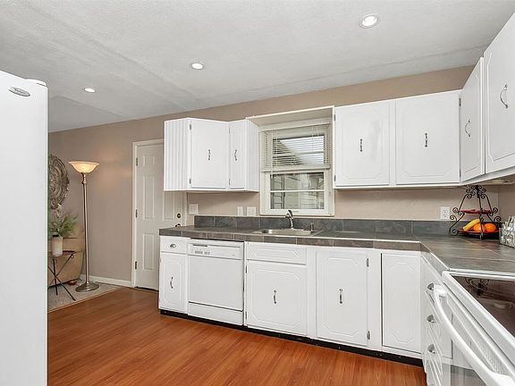 Kitchen is white and has an eating space on the other side.