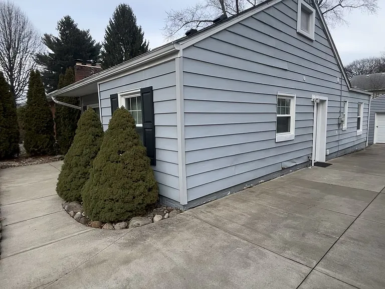Wide, private concrete driveway connected to a picturesque front porch seating/table area. Side entry door.