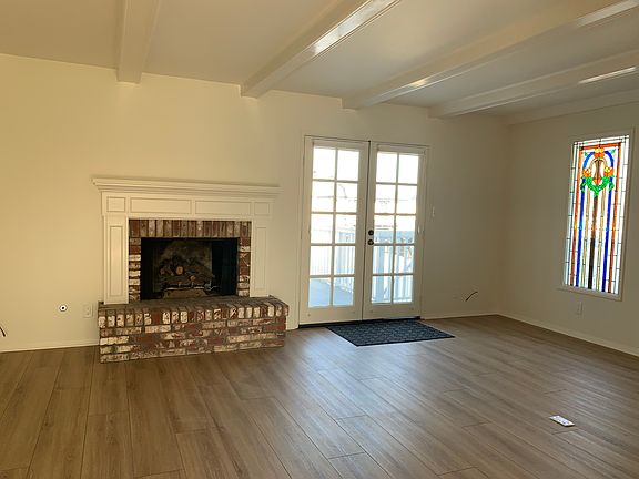 Spacious living room has a gas fireplace with mantle and beams on the ceiling.