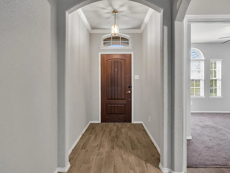 Entryway featuring a paneled wood door, transom window with arched detailing, and wood-finish flooring