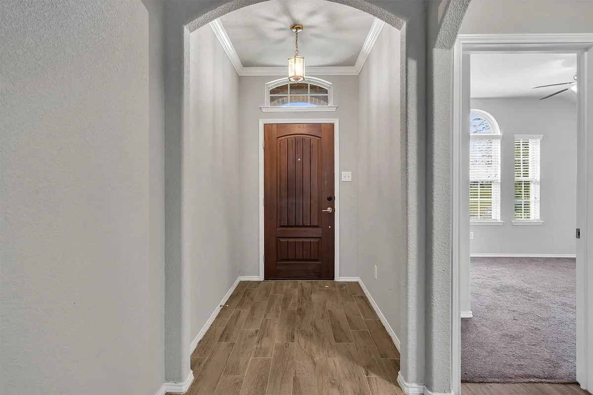 Entryway featuring a paneled wood door, transom window with arched detailing, and wood-finish flooring - 4080 Serene Dr