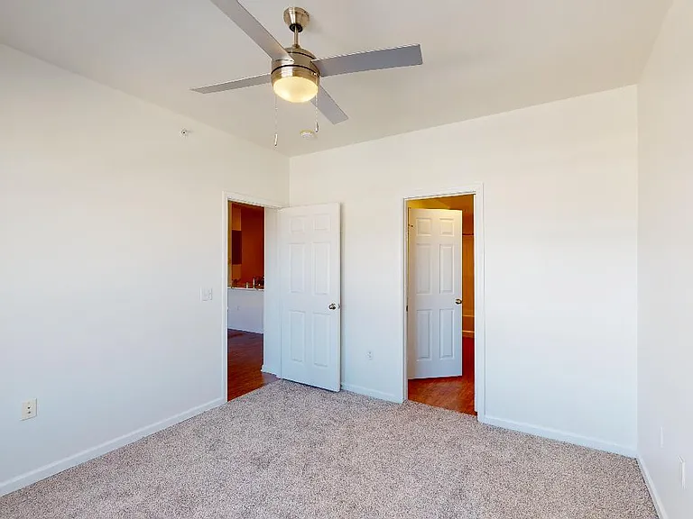 Spacious apartment bedroom with attached bathroom and plush carpet flooring.