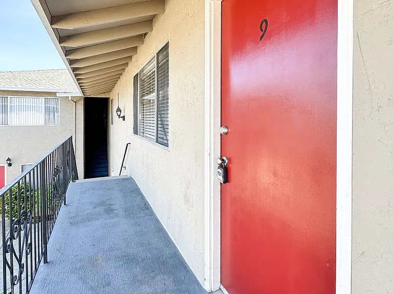 a red door at the entrance to a building with a balcony