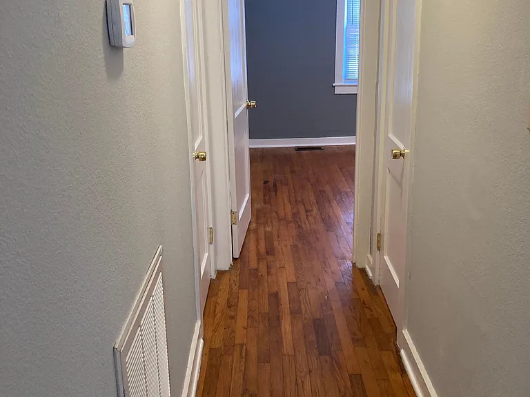 Hallway leading to two bedrooms, with storage closets on the left and right.