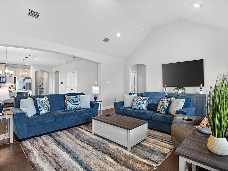 Spacious living area featuring wood-finish flooring, vaulted ceilings, and recessed lighting