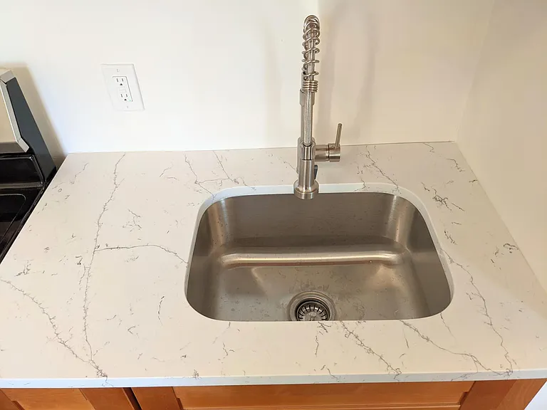 Beautiful quartz countertops, deep stainless steel sink, and commercial style spray hose faucet