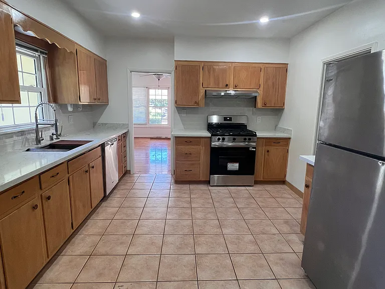 Brand new kitchen with new quartz countertops and backsplash, new gas range and exhaust fan, new kitchen sink and faucet, and a new disposal. Fridge and dishwasher also present.