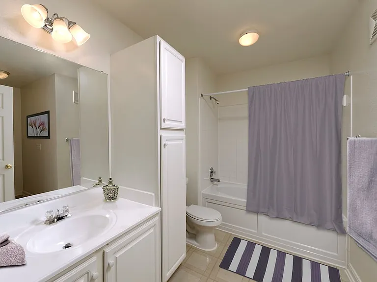 Classic Package bath white white cabinetry, white laminate countertops, and vinyl tile flooring
