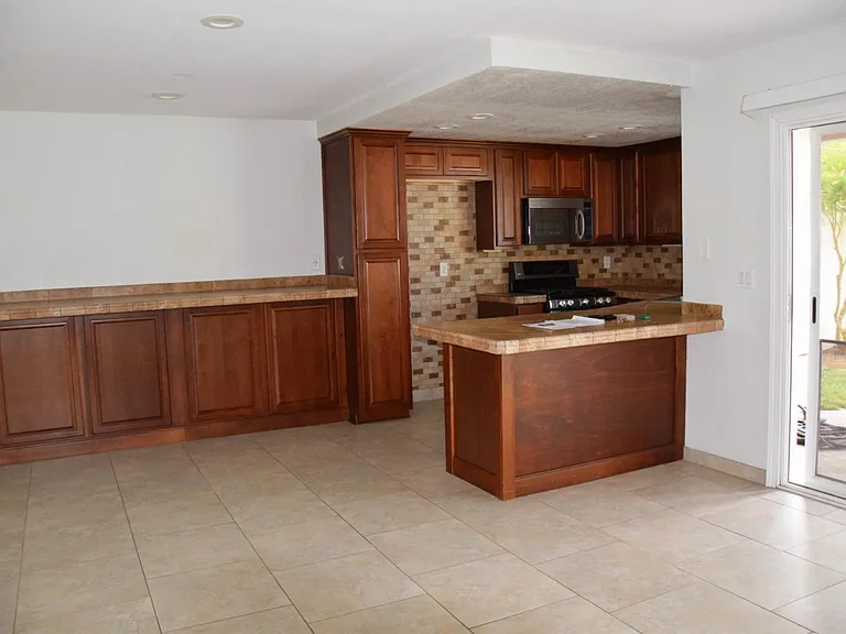 Breakfast counter on left with storage cabinets under. Slider to back yard on right.