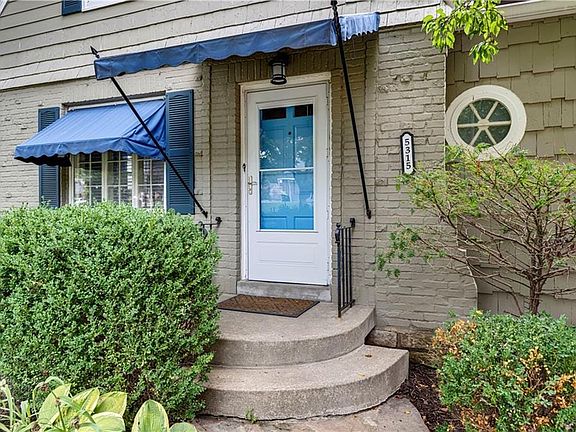 Inviting entry featuring a white door with a vibrant blue inner door, concrete steps, and a wrought iron handrail