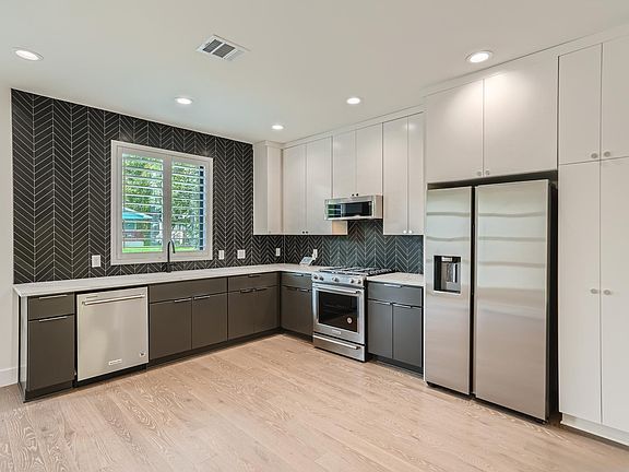 Upscale kitchen features new stainless steel appliances, lots of cabinet space, and quartz countertops and tile backsplash.