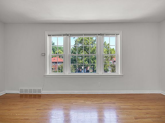 Natural light-filled Living room with gleaming hardwood floors and a picture window framing serene neighborhood views