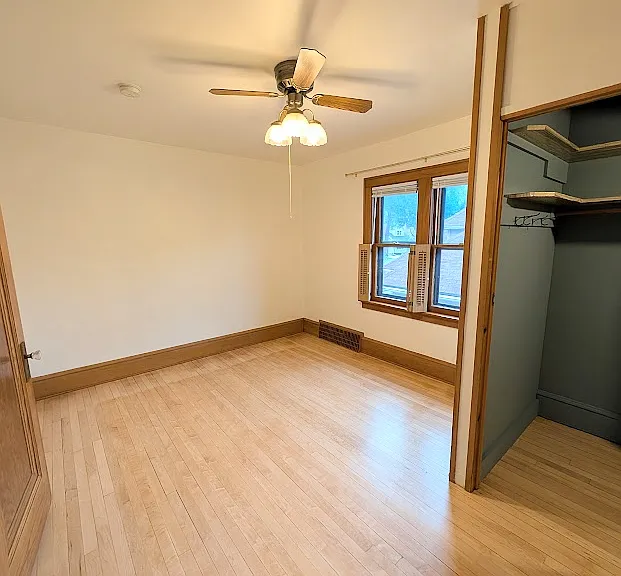 [UPPER UNIT]: First bedroom with shutter style window covers and blinds. Double sized closet