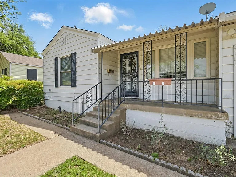 White siding exterior with a covered front porch, wrought iron railing, concrete steps, and a security screen door