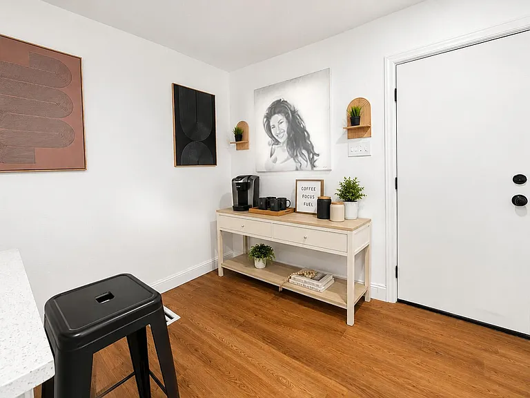 Welcoming entry area with console table, wood-look flooring, and a convenient coffee station with storage below.