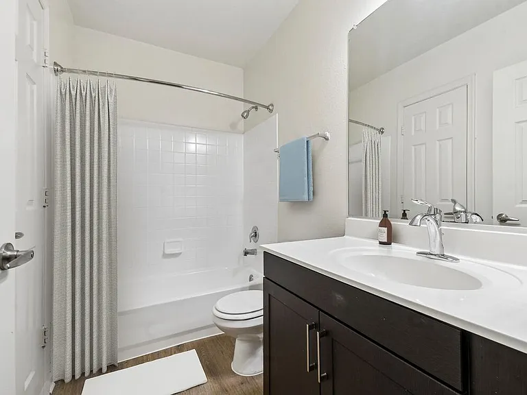 Renovated Package I bath with espresso cabinetry, white laminate countertops, and hard surface flooring