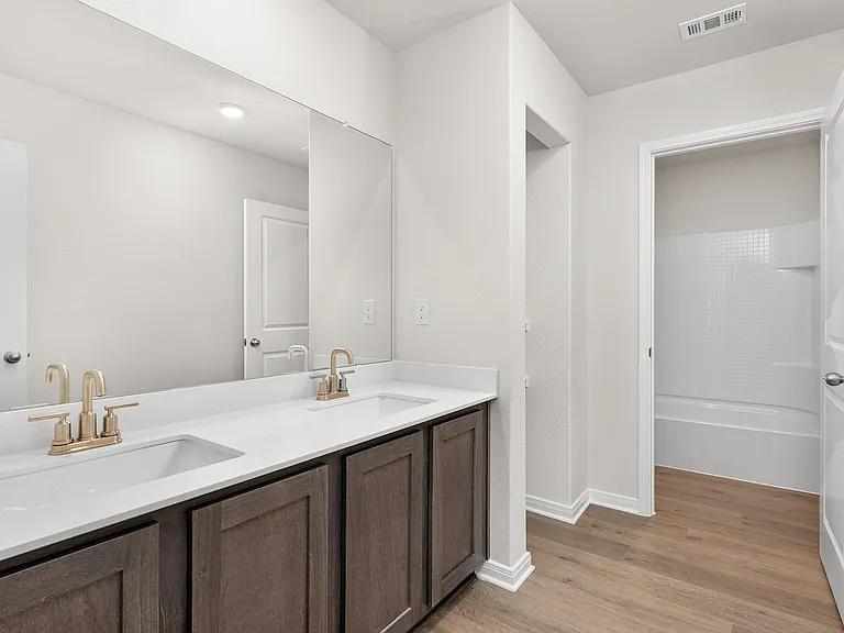 The secondary bathroom has a sprawling dual-sink vanity and a shower-tub combo.