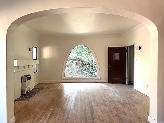 Light filled living room with high ceilings and restored, real hard wood floors. (Heater on left will be updated before move-in.)