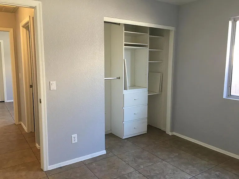 This bedroom has lots of built-in shelving in the closet.