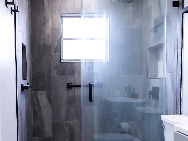 shared bathroom featuring brand new floor to ceiling tiled shower and remodeled bathroom.