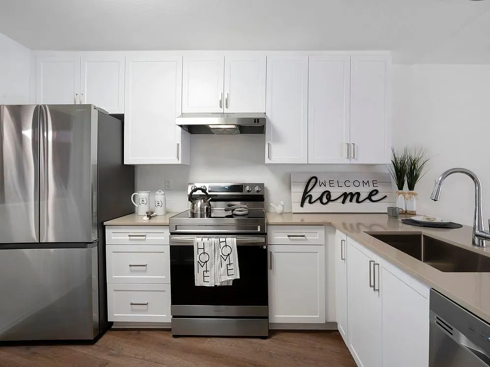 Renovated Package I kitchen with stainless steel appliances, light grey quartz countertops, white cabinetry, and hard surface flooring - eaves Phillips Ranch
