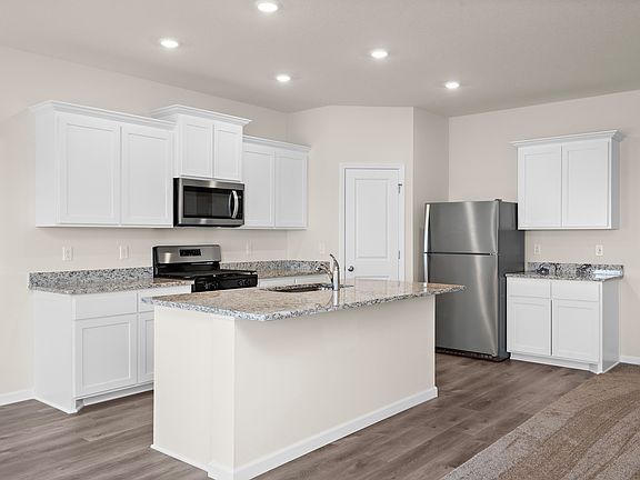 The kitchen has stainless steel appliances and plank flooring.
