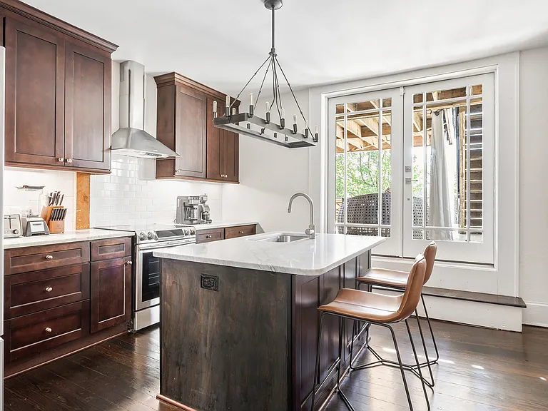 Fully stocked kitchen with dishware and appliances. Features marble countertops, new leather bar chairs, and stylish wooden accent wall.