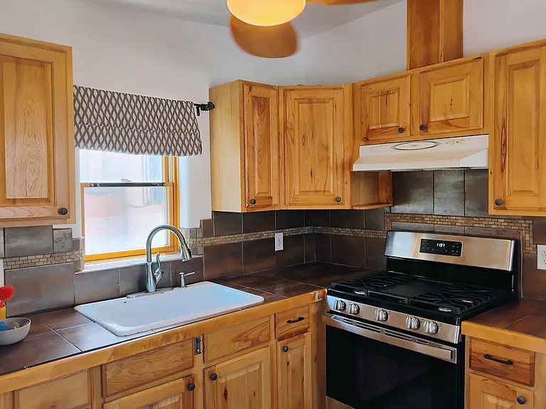 Wood window, Hickory Wood Cabinets, tiled counter top and back splash. Large sink .