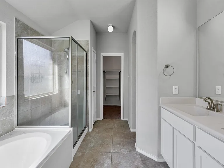 Bathroom featuring a glass-enclosed shower, separate soaking tub, and a dual vanity with a large mirror