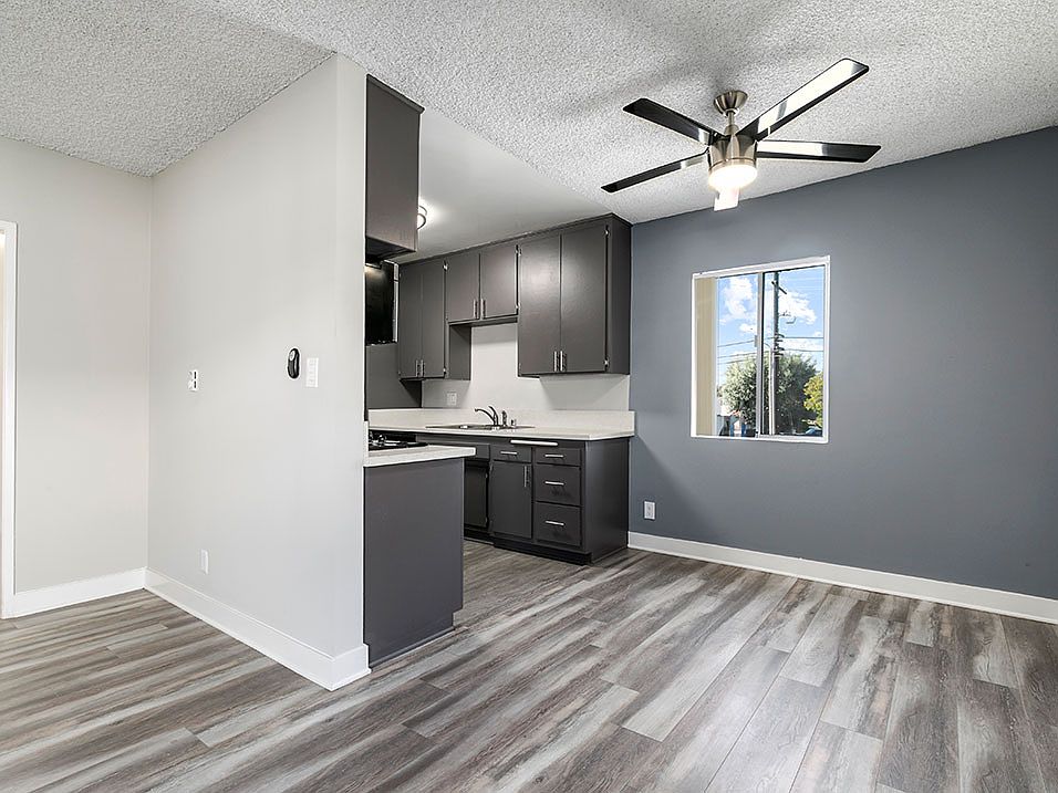 Hardwood floor living room view of kitchen and ceiling fan over dining area.