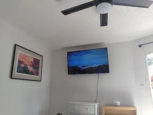 Bedroom with ceiling fan and wall mounted flat screen TV.